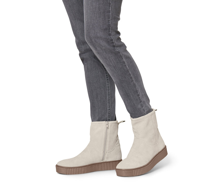 Beine in grauen Jeans tragen beige Veloursleder-Boots.