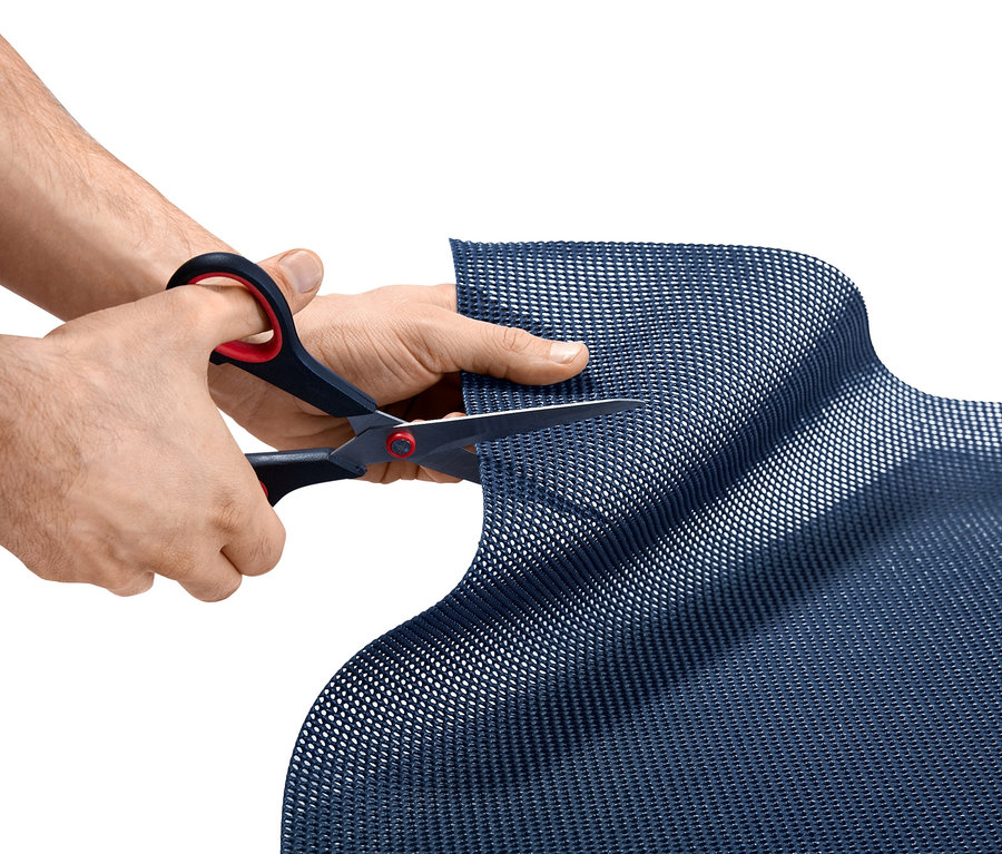 Mann schneidet mit einer Schere einen blauen Zeltteppich, ca. 220 x 350 cm.