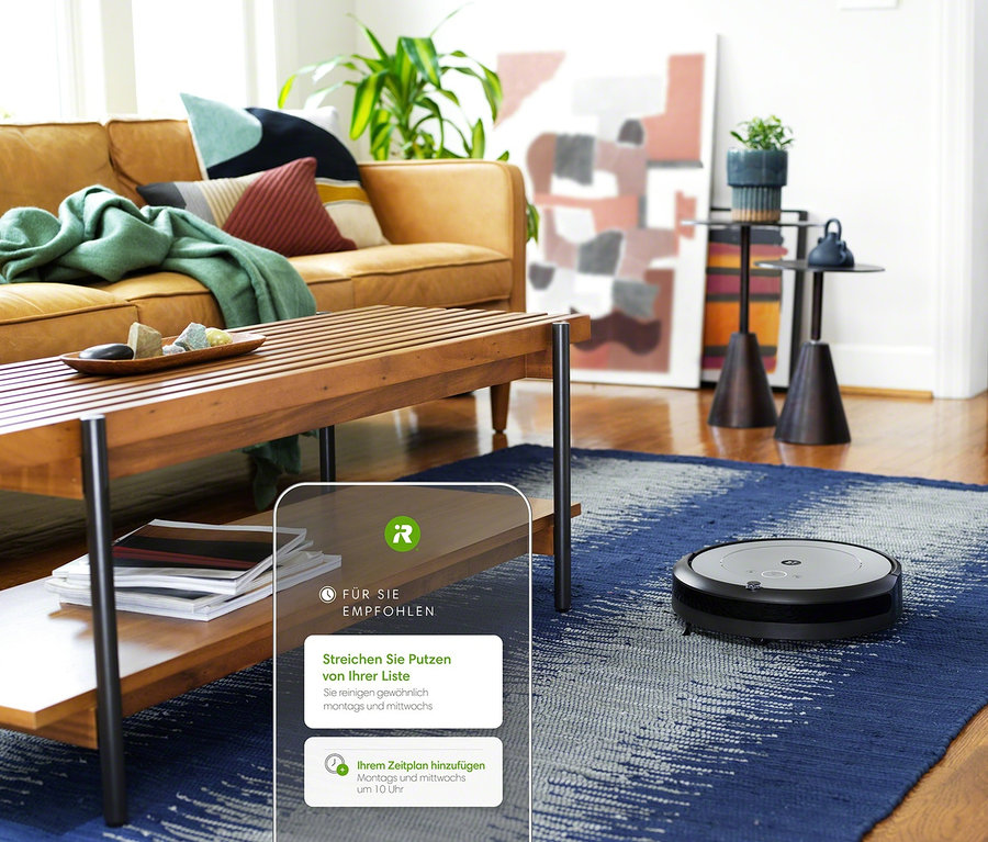 Im Wohnzimmer saugt ein iRobot Roomba i1 Saugroboter auf einem blauen Teppich.