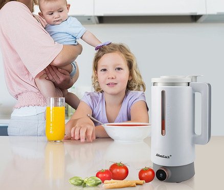 Mutter hält Baby, daneben Mädchen an Schüssel, Glas Saft und Steba Vegan-Drink-Maker »VDM 2 HOT & COLD«.