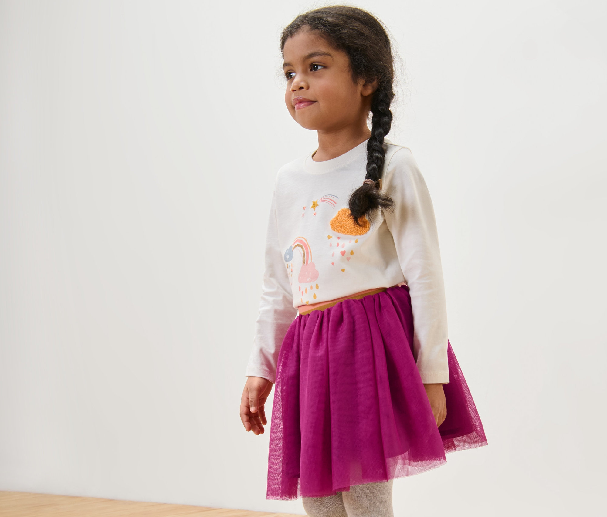 Mädchen trägt ein weißes Langarmshirt und einen Kinder-Tüllrock.