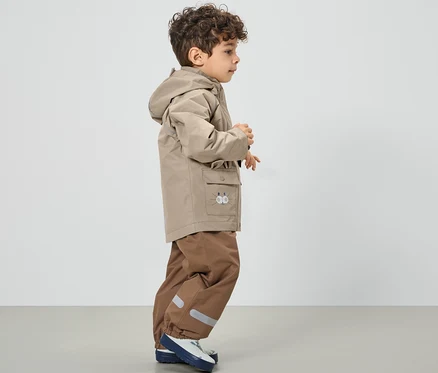 Junge trägt eine braune Kinder-Regenjacke.