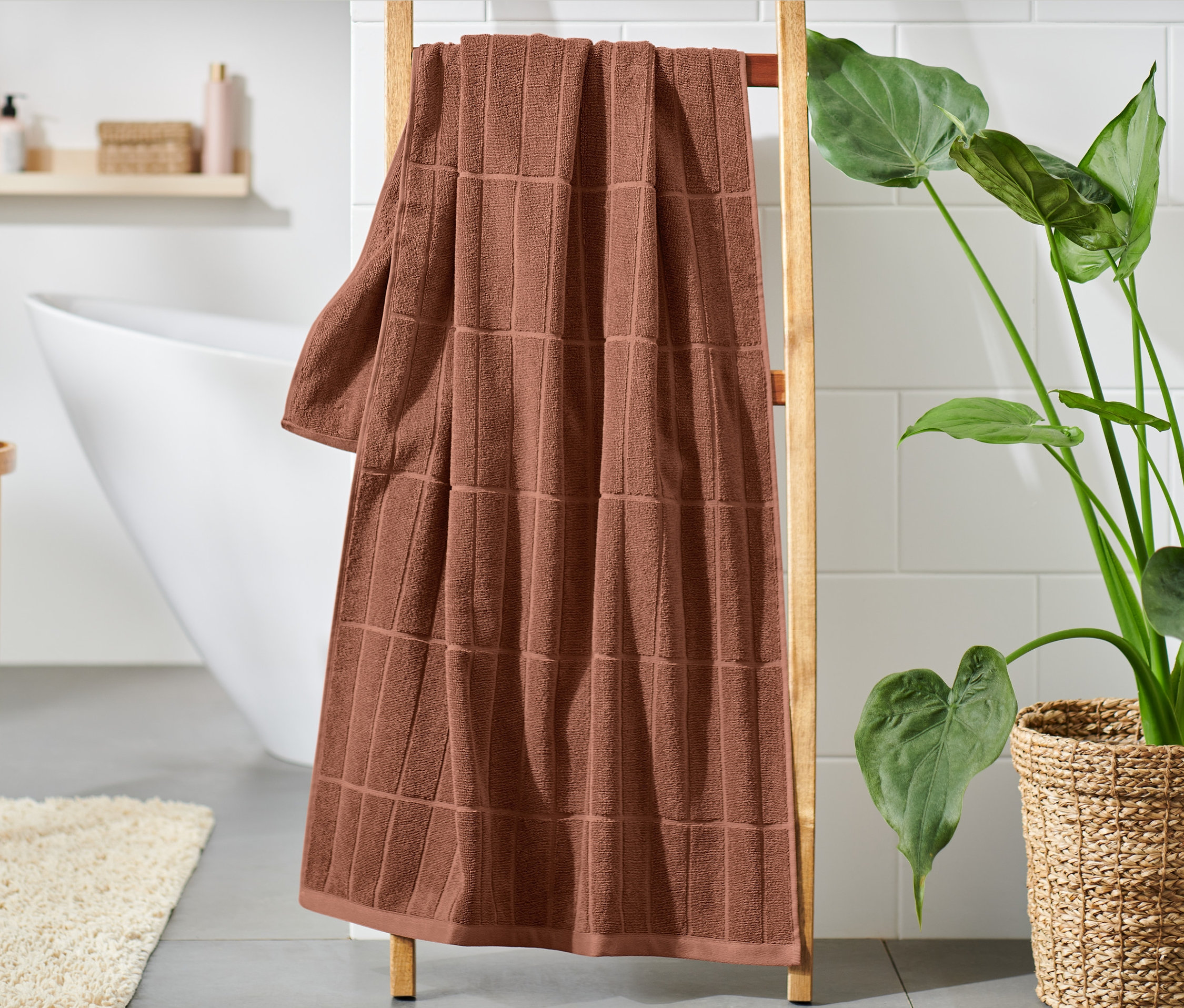 Ein Badetuch in Premiumqualität, rostrot, hängt auf einer Holzleiter im Badezimmer.