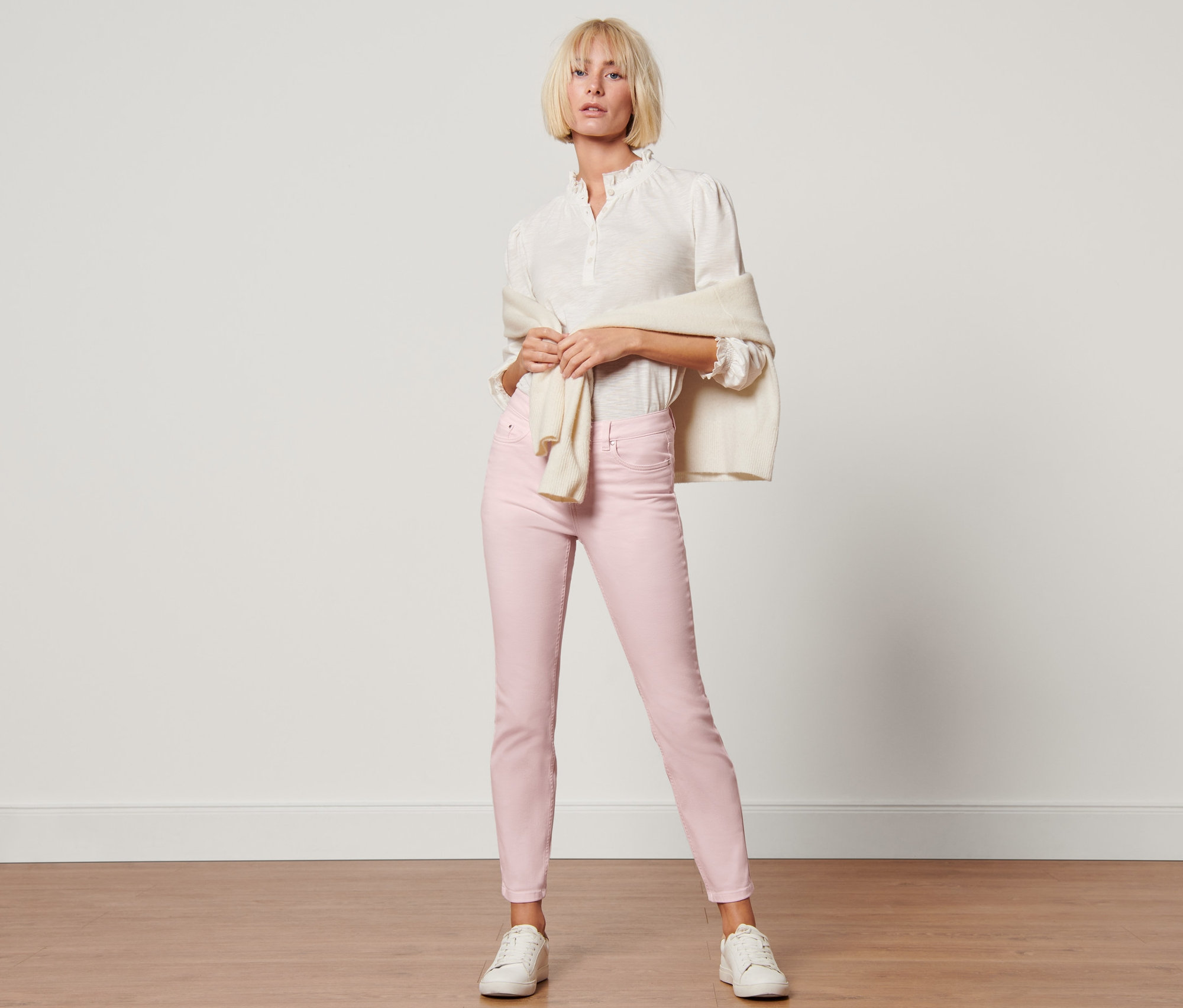 Frau posiert in rosa Colored Denim »Fit Emma«, weißem Hemd und weißen Turnschuhen.