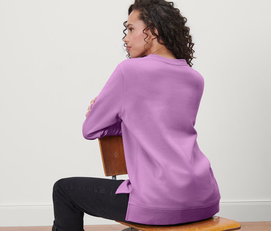 Frau sitzt auf einem Stuhl und trägt ein Sweatshirt.