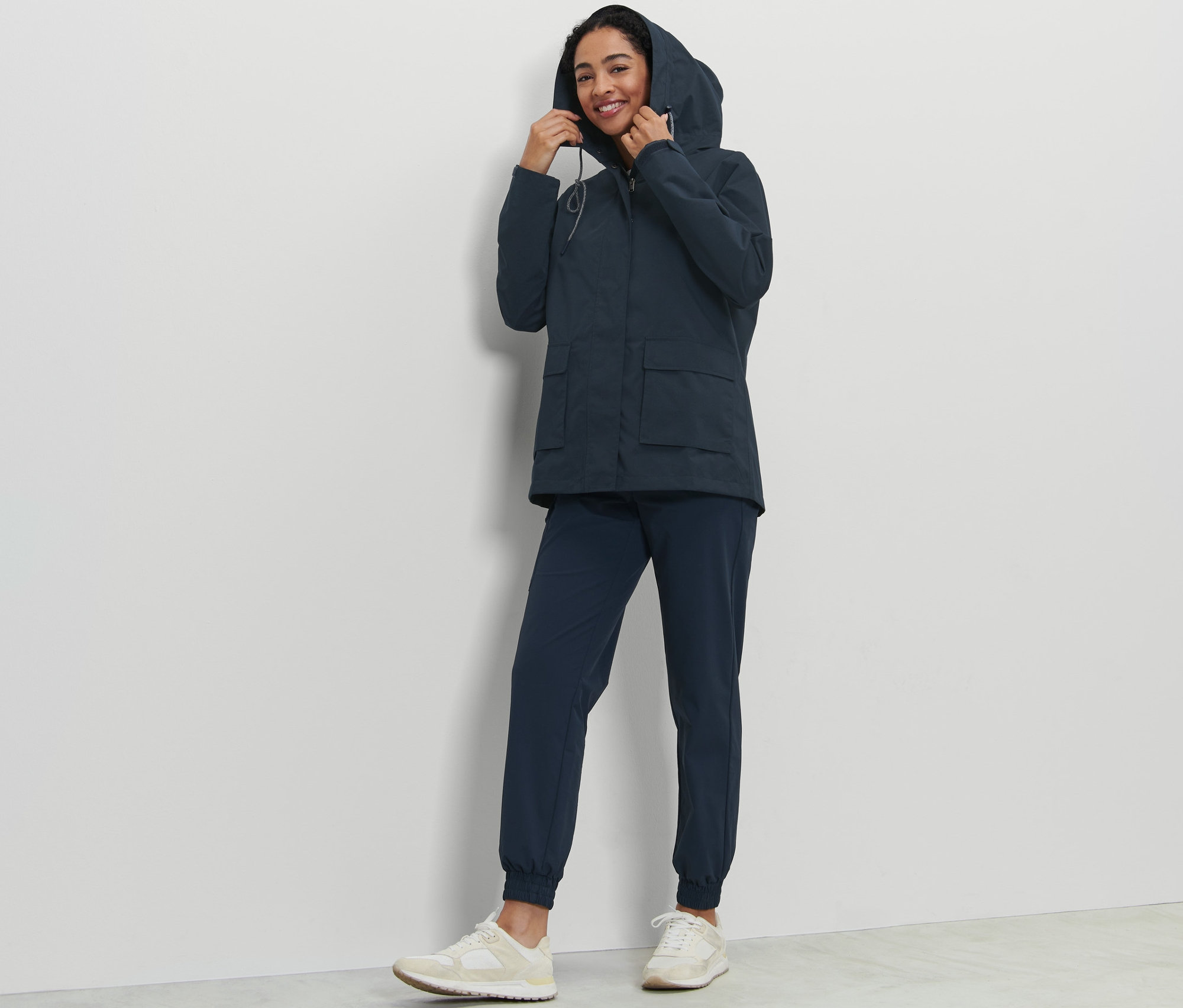 Frau justiert die Kapuze ihrer Allwetterjacke.