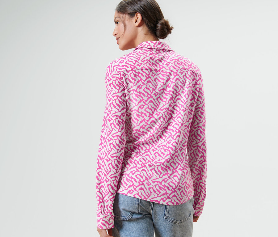 Frau trägt ein Blusenshirt mit Knopfleiste und Jeans.