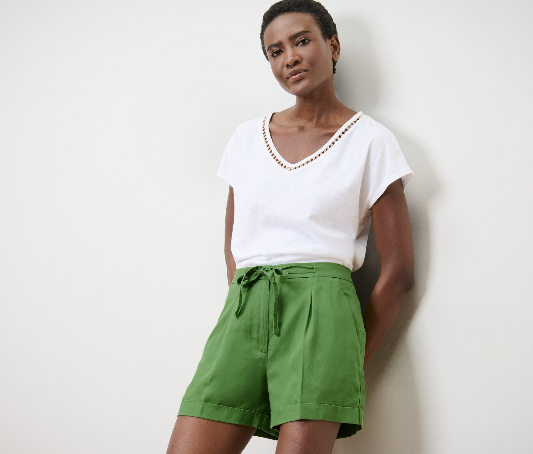 Frau posiert in grünen Leinen-Shorts und weißem T-Shirt.