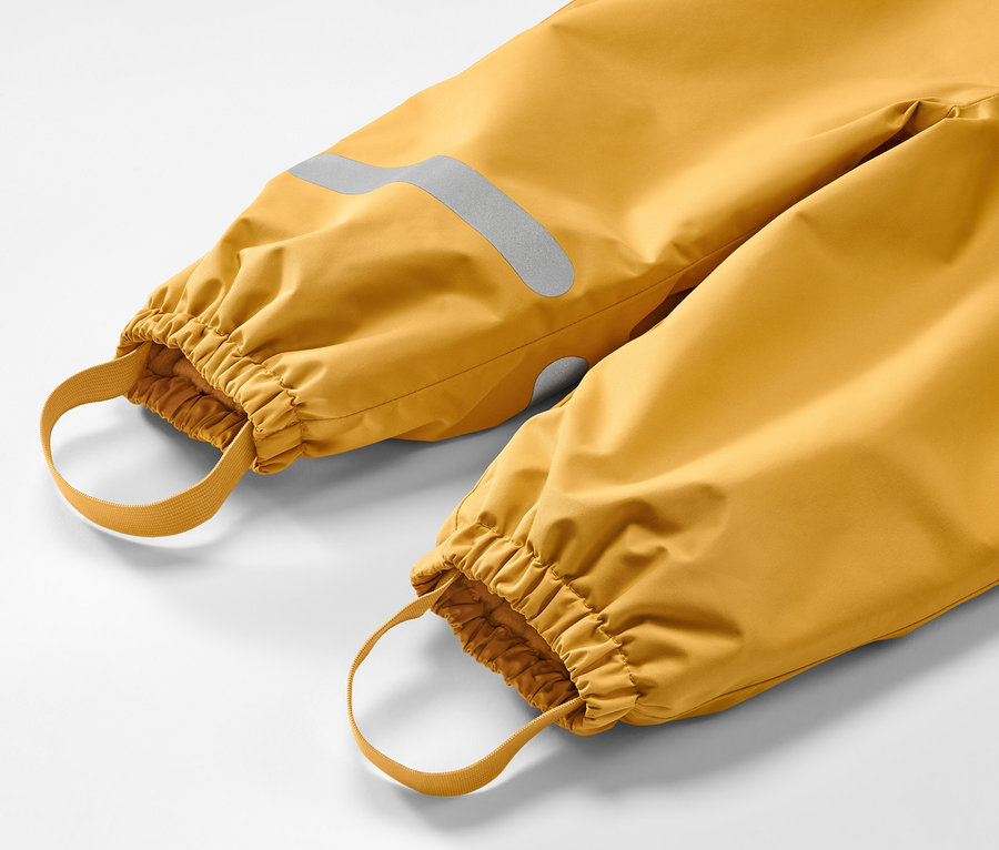 Detailaufnahme einer gelben Kinder-Thermo-Regenhose mit Reflektor und Gummibändern.