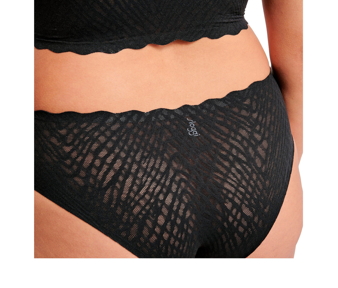 Person von hinten, trägt schwarze sloggi ZERO Feel Bliss Hipster und passendes Oberteil. Beide haben ein transparentes, strukturiertes Muster und gewellte Kanten.