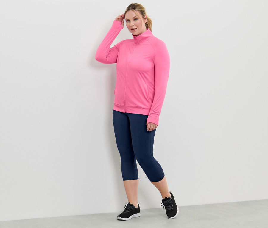 Frau trägt eine pinke Funktionsjacke und marineblaue Leggings.