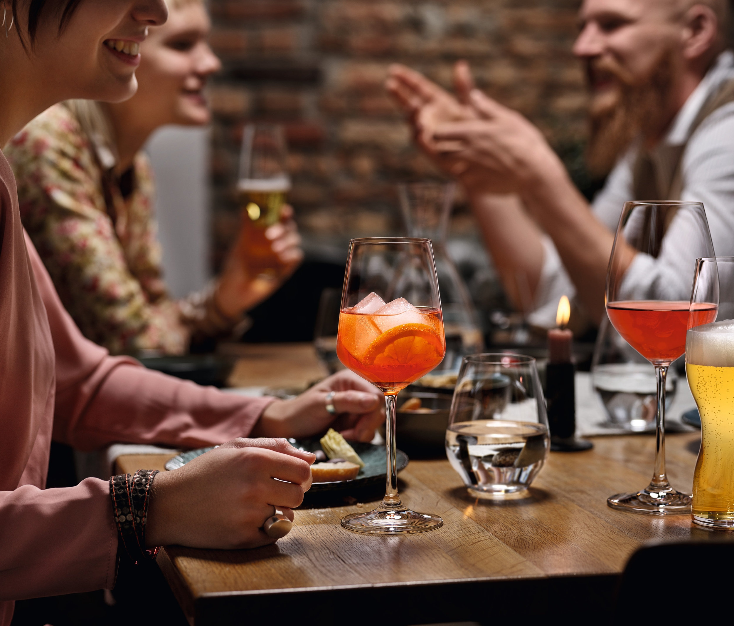 Vier Personen sitzen an einem Tisch mit Getränken in Gläsern. Auf dem Tisch stehen Spiegelau Weißweingläser »Style« im 8er-Set.