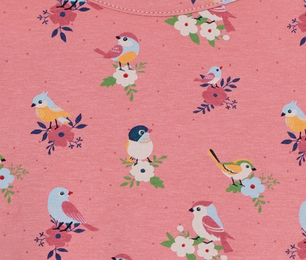 Detail eines rosa Kleinkind-Jerseykleids mit Vogel- und Blumenmuster.