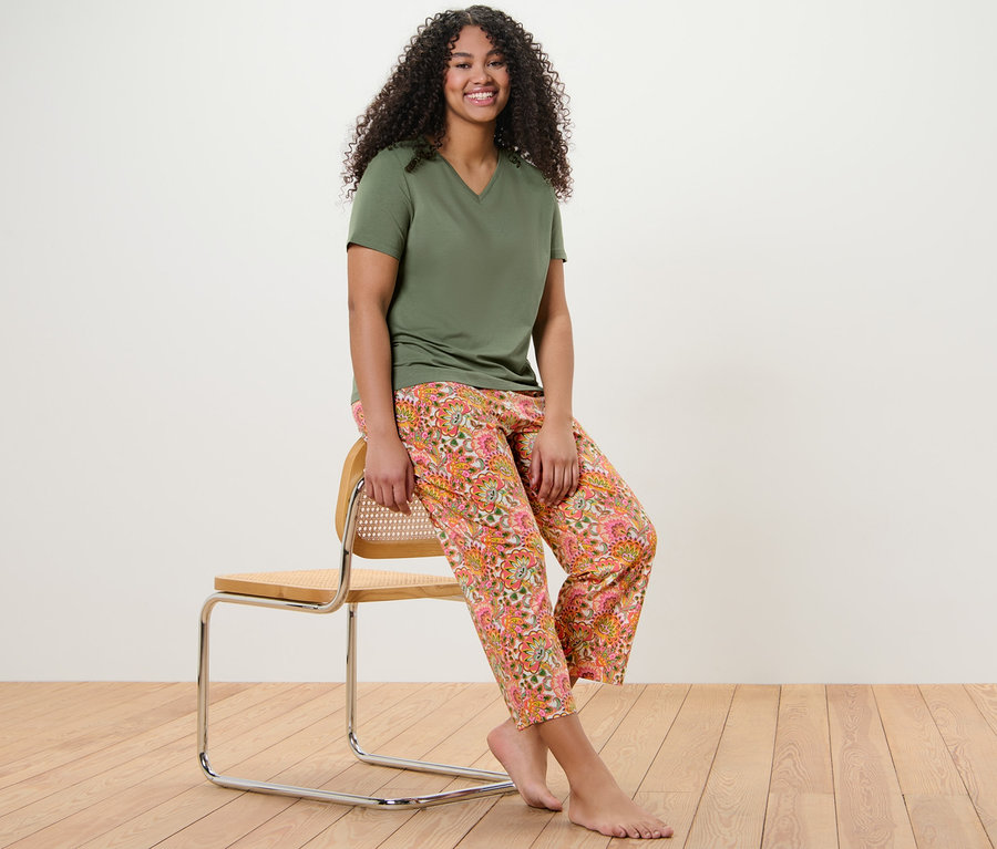 Frau sitzt auf einem Stuhl und trägt einen Pyjama.