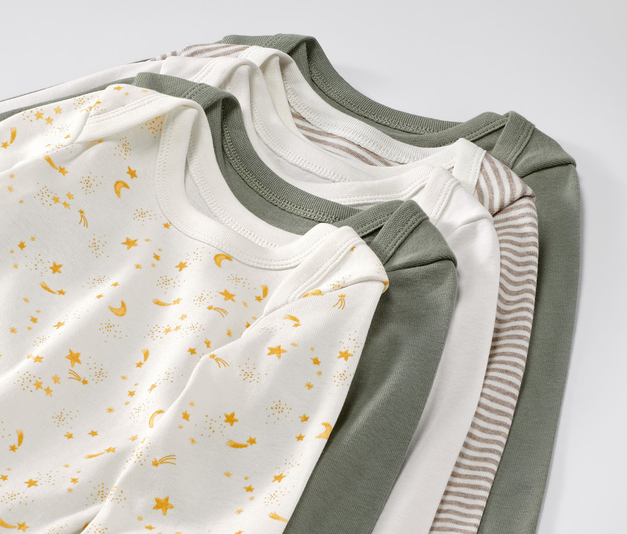 Fünf Baby-Bodys mit Mitwachsfunktion und Sternen liegen übereinander.