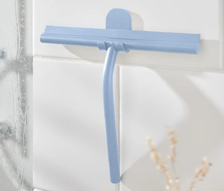 Blauer Badwischer mit Wandhalterung an weißen Fliesen neben der Dusche.