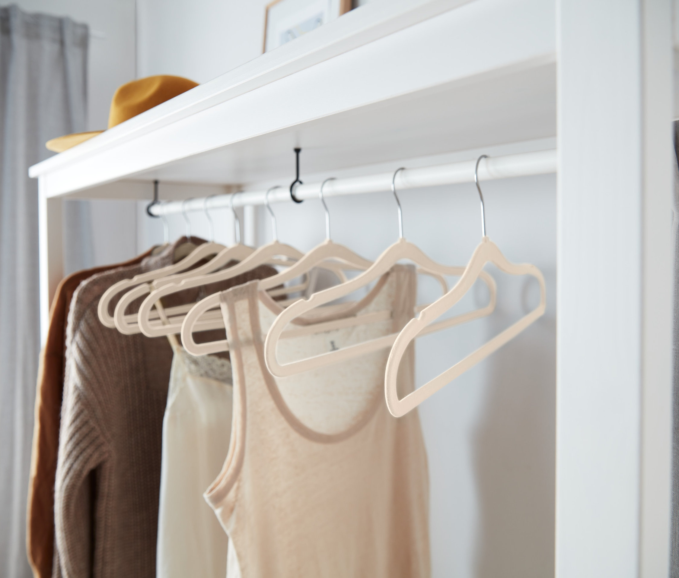 Kleidung hängt an 8 beigen, extraschmalen Kleiderbügeln.