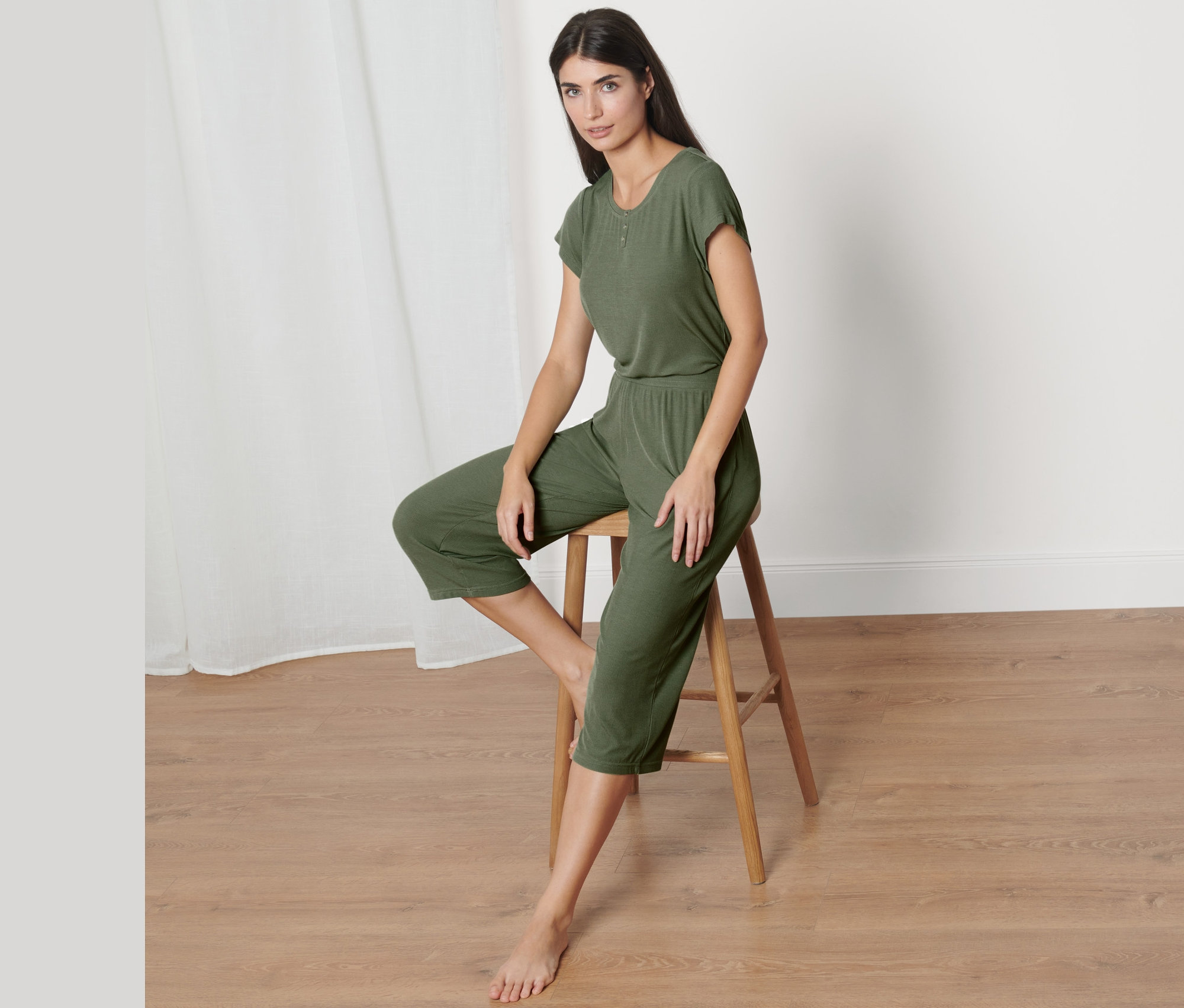 Frau sitzt auf Hocker und trägt grünen Pyjama aus Rippe.