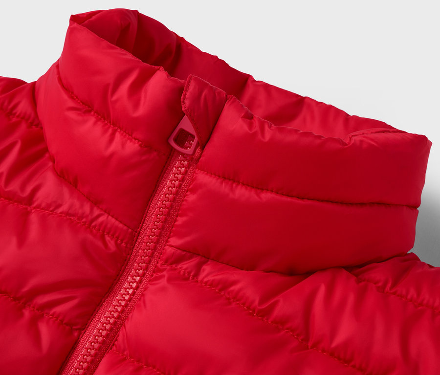 Detailaufnahme einer roten Steppjacke mit Kragen und Reißverschluss.