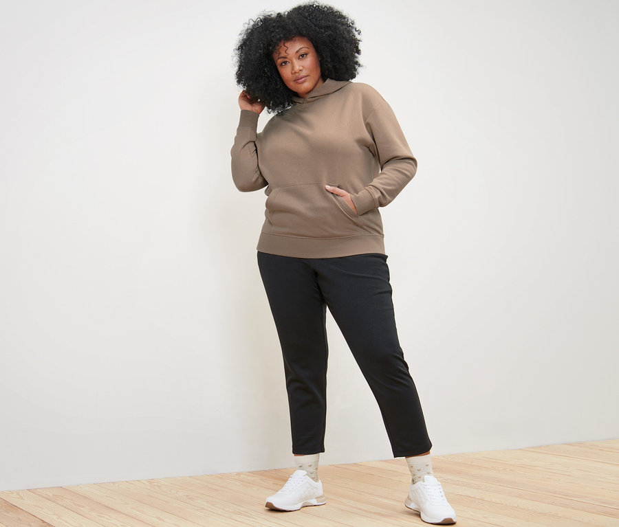 Frau posiert in beigem Hoodie.