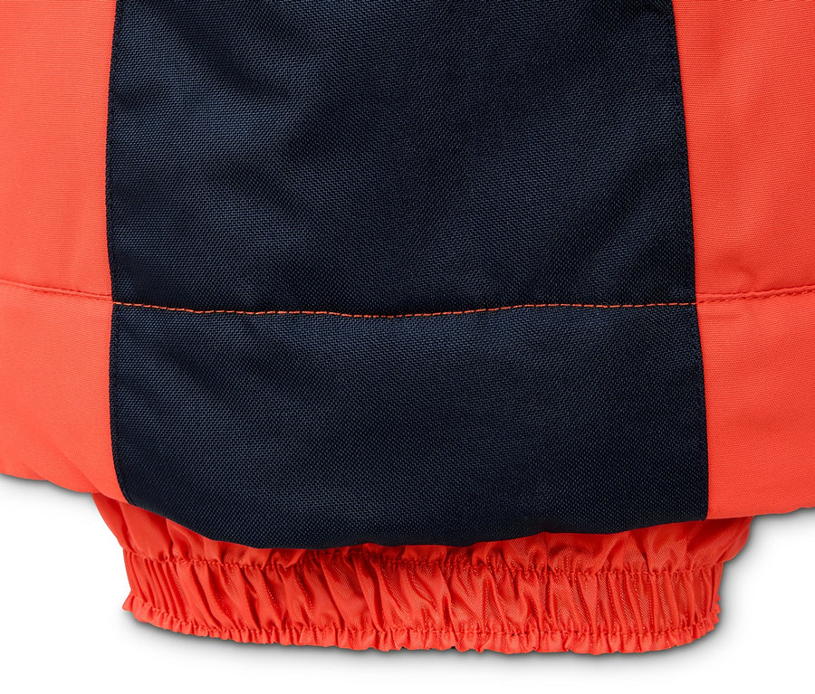 Detail einer orangefarbenen Snowboardhose mit dunkelblauer Verstärkung.
