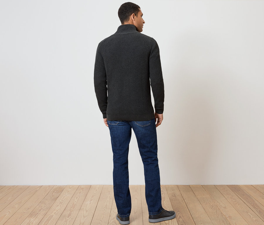 Mann von hinten trägt einen dunkelgrauen Reißverschluss-Pullover, Jeans und Schuhe.