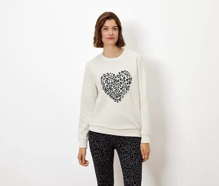 Frau trägt ein weißes Sweatshirt mit einem Tierdruckherz und Leggings mit Tierdruck.