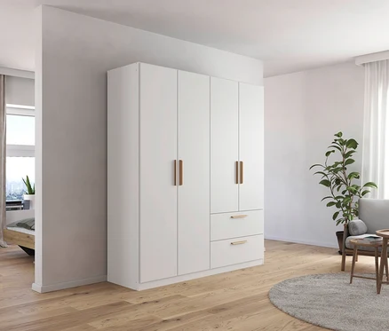 Ein Zimmer mit einem weißen, 4-türigen Drehtürenschrank »Skandi« von Rauch, einem grauen Sessel und einem Couchtisch aus Holz.