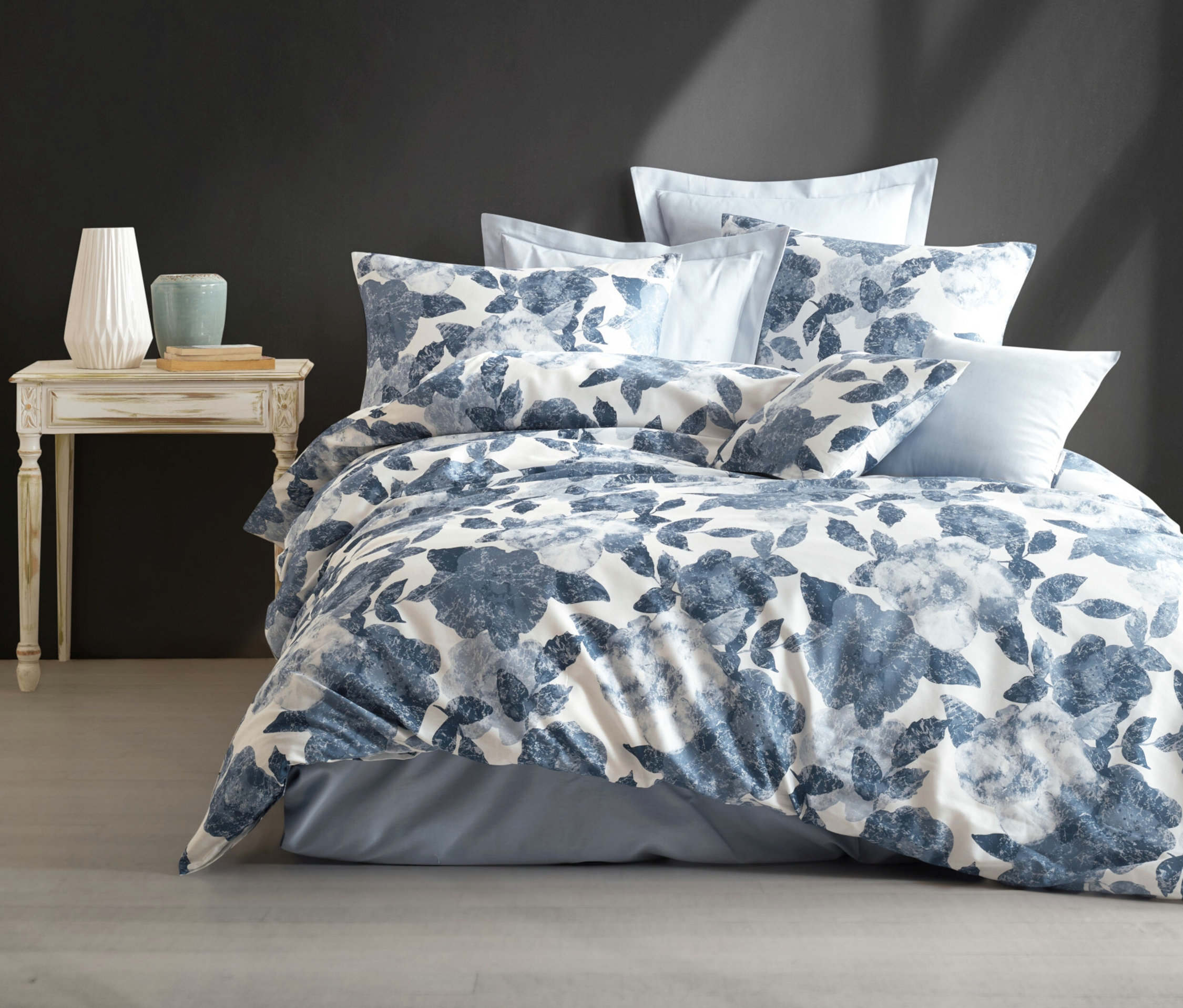 Helles blaues Bettwäsche-Set »Elisa« von SCHIESSER mit Botanik-Print auf einem Bett neben einem Tisch mit Vasen.