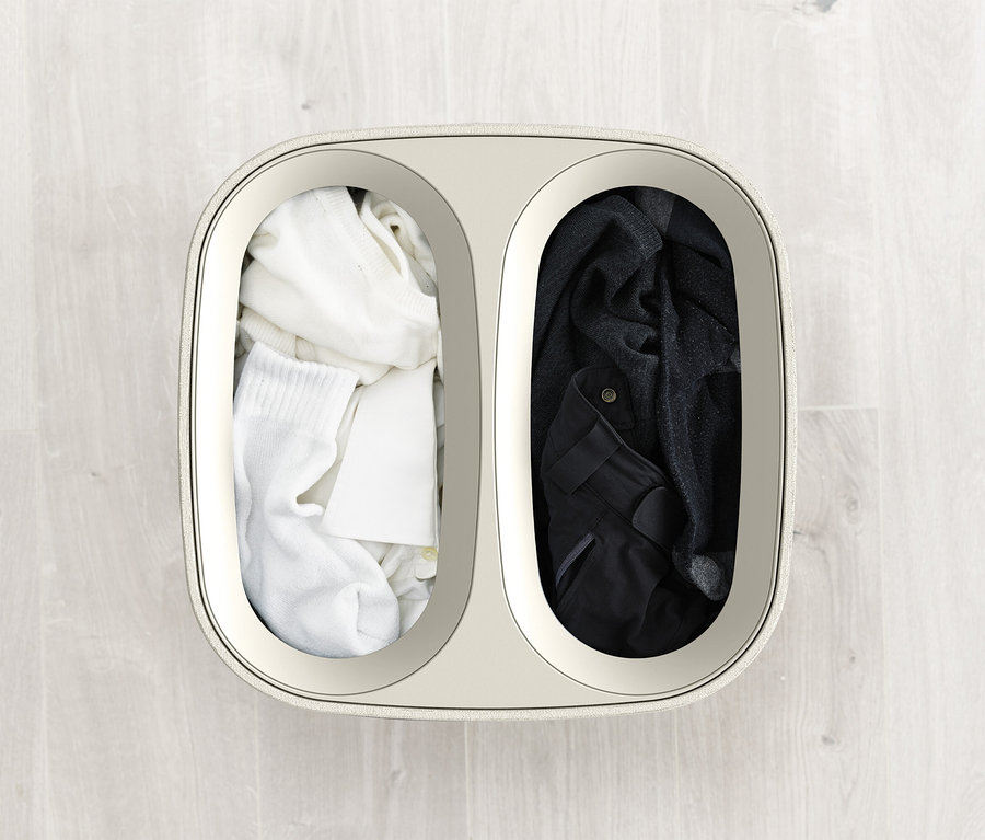 Draufsicht auf einen Wäschekorb, der in zwei Teile geteilt ist, einer mit weißer Kleidung und der andere mit dunkler Kleidung.