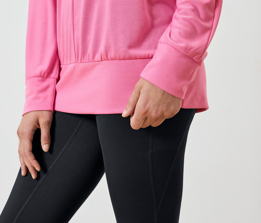 Detailaufnahme einer Frau mit rosafarbenem Sweatshirt und schwarzen Leggings.