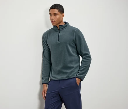 Mann trägt grünes Fleece-Halbarm-Oberteil mit marineblauen Hosen.
