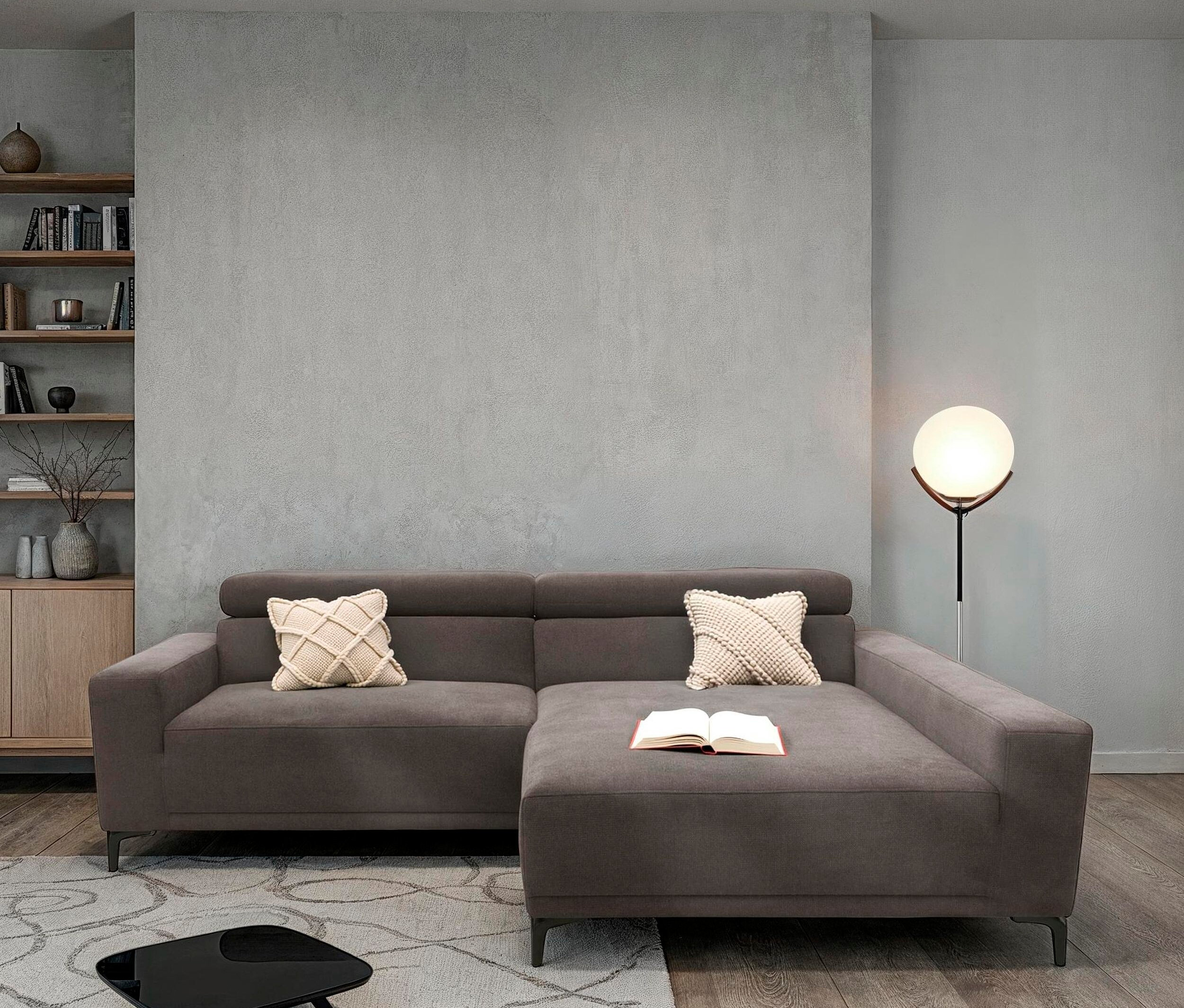 Graues Sofa mit Kissen und Buch im Wohnzimmer.