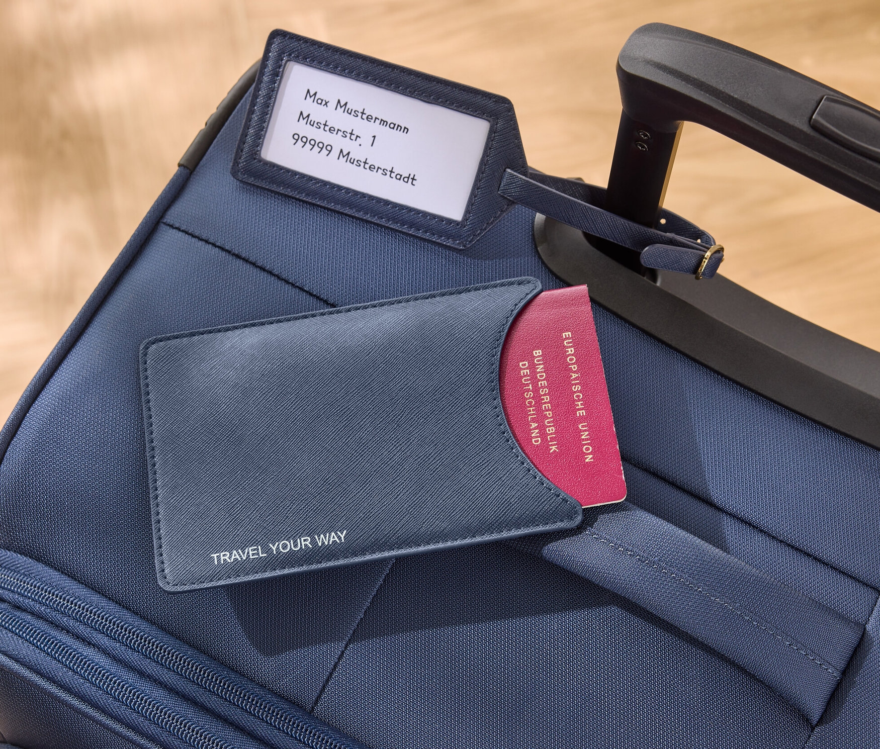 Auf einem blauen Koffer liegen eine blaue Passhülle und ein Kofferanhänger.