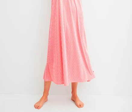 Frau posiert in einem langen, rot-weiß gestreiften Sommerkleid.
