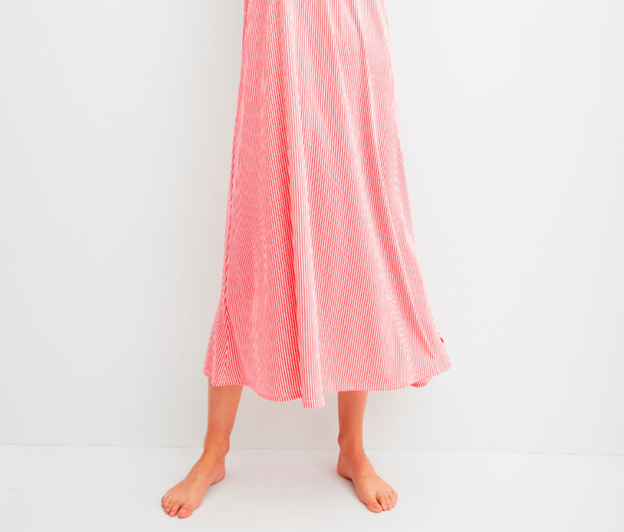 Frau posiert in einem langen, rot-weiß gestreiften Sommerkleid.