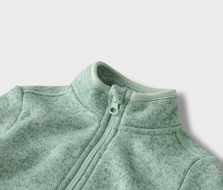 Nahaufnahme einer hellgrünen Fleecejacke mit Reißverschluss.