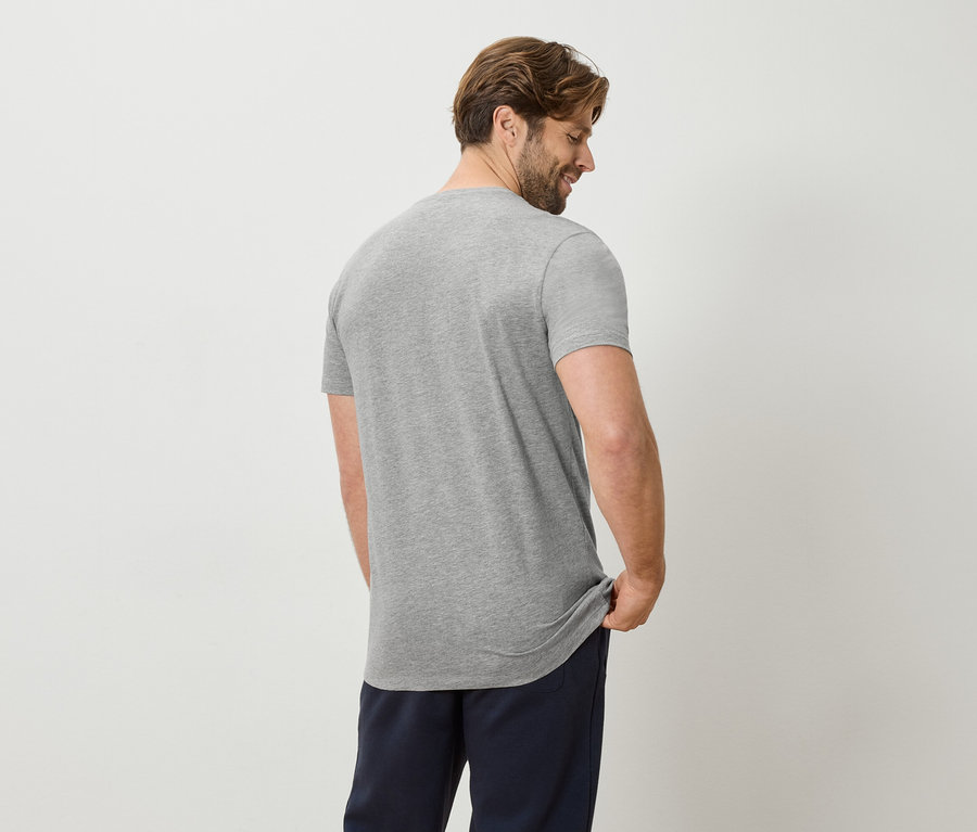 Mann von hinten in grauem T-Shirt und blauer Hose.