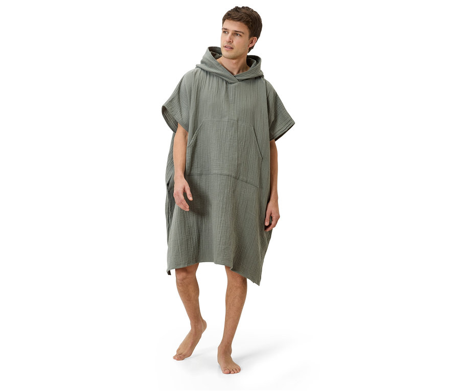 Mann steht barfuß auf weißem Grund und trägt einen olivgrünen Kapuzenponcho.