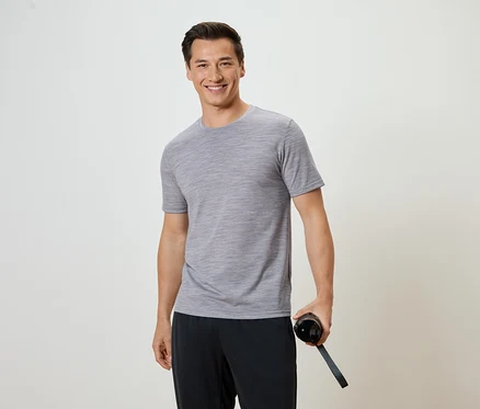 Mann mit grauem T-Shirt und schwarzer Hose hält eine Wasserflasche.