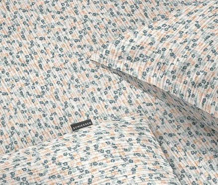 Nahaufnahme von Bettwäsche mit blauem und orangefarbenem Blumenmuster.
