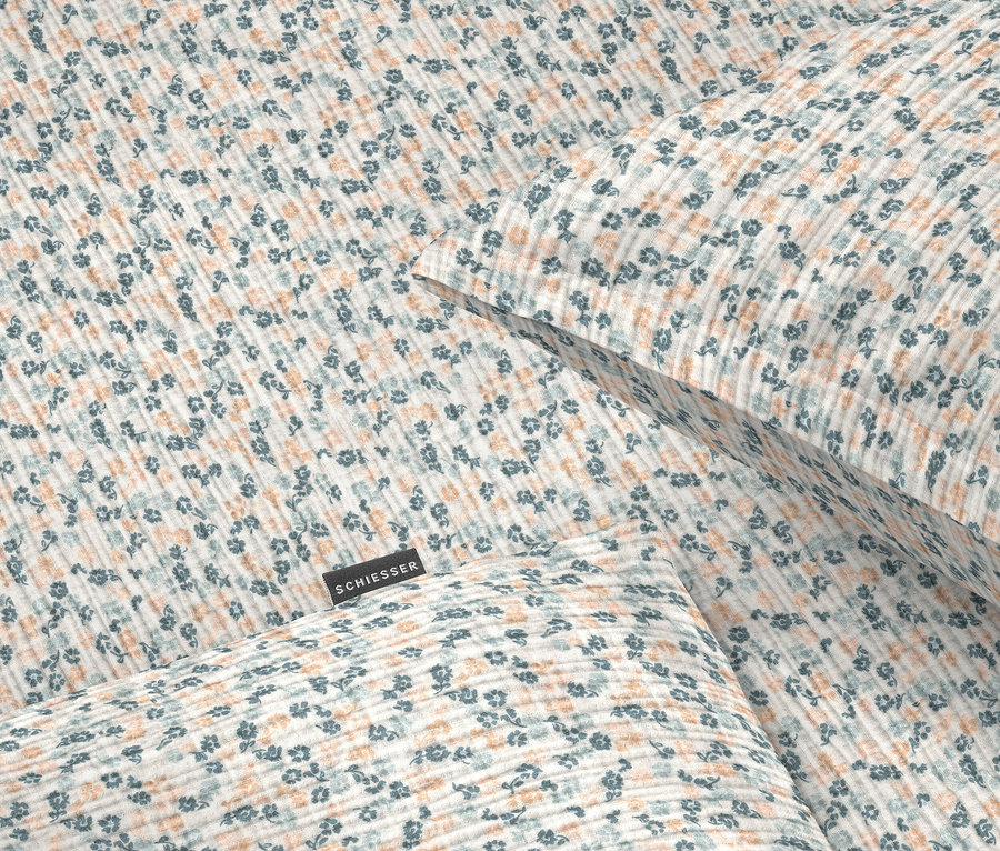 Nahaufnahme von Bettwäsche mit blauem und orangefarbenem Blumenmuster.