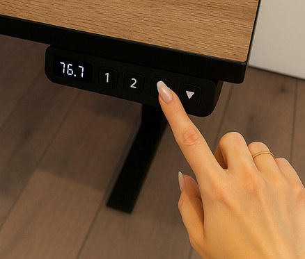 Eine Hand drückt einen Knopf an einem elektrisch höhenverstellbaren Schreibtisch mit Kabelführung.