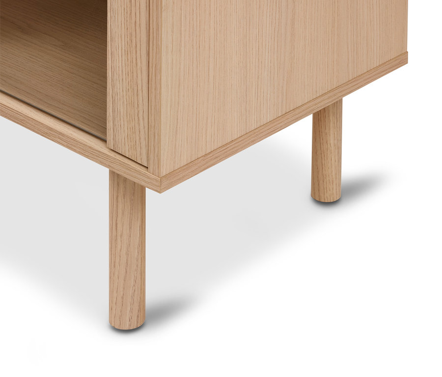 Nahaufnahme der unteren Ecke eines hellen Holzschranks mit zwei runden Holzbeinen, die ein offenes Fach zeigt.