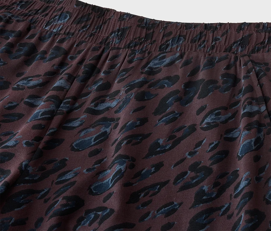 Nahaufnahme einer dunkelbraunen Hose mit elastischem Bund und blauem sowie schwarzem Leopardenmuster. Eine Taschenöffnung ist auf der rechten Seite sichtbar.