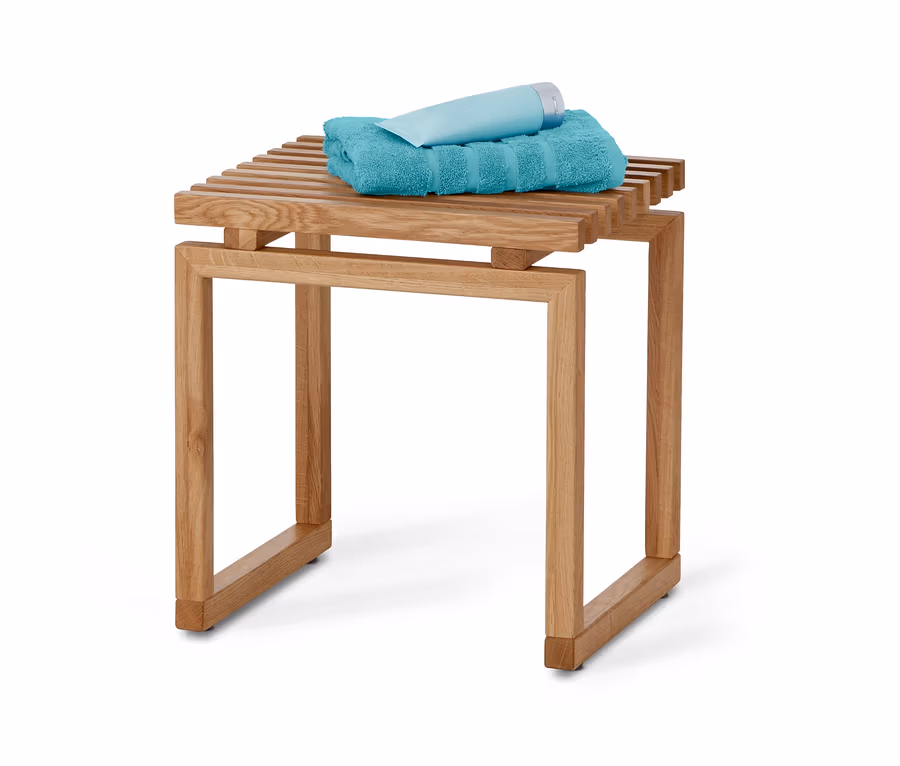Auf einem Holzhocker liegen ein türkises Handtuch und eine hellblaue Tube.