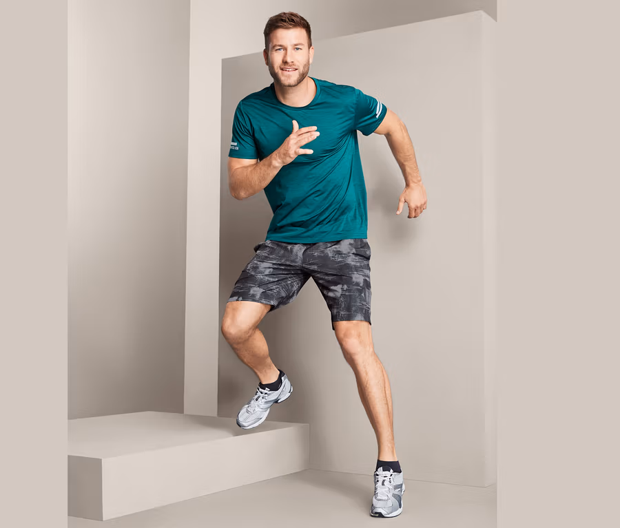 Mann in grünem T-Shirt und Funktionsshorts läuft Treppen hoch.