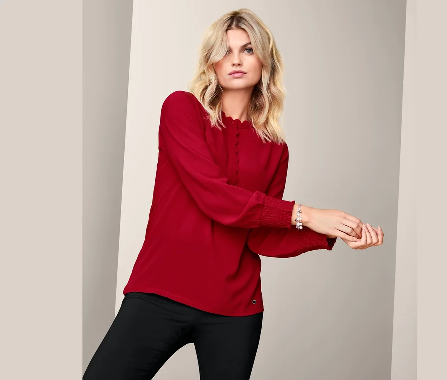 Frau posiert in rotem Blusenshirt.