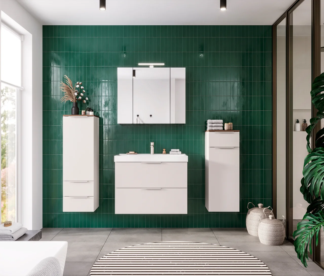 Modernes Badezimmer mit grüner Fliesenwand, einem weißen schwebenden GW Waschtisch »Lasino« mit hohem Becken, einem Spiegelschrank und zwei hohen weißen Hängeschränken. Links ein Fenster, rechts eine Dusche, auf dem grauen Boden ein runder gestreifter Teppich.