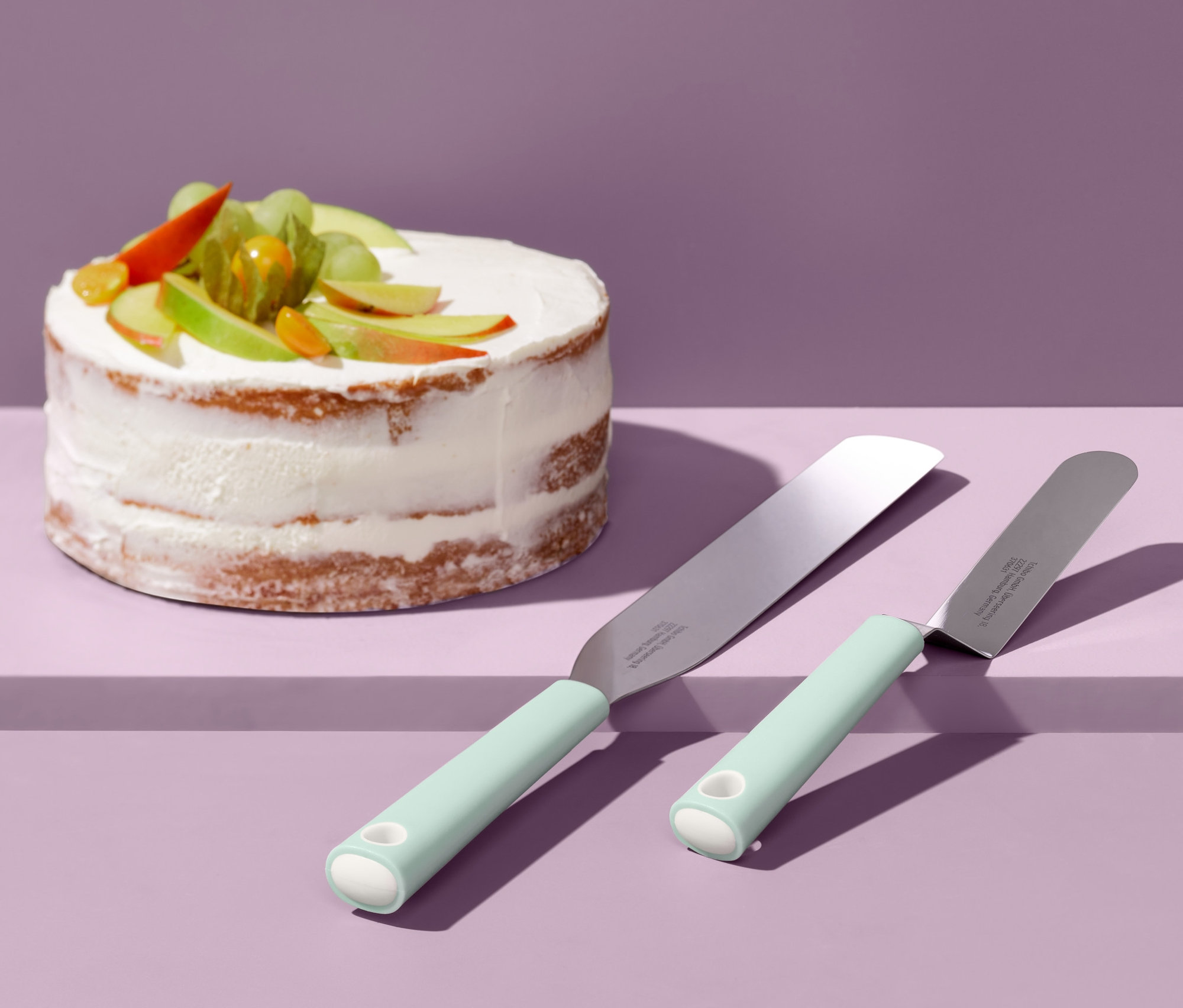 Zwei Streichpaletten liegen neben einem verzierten Kuchen.